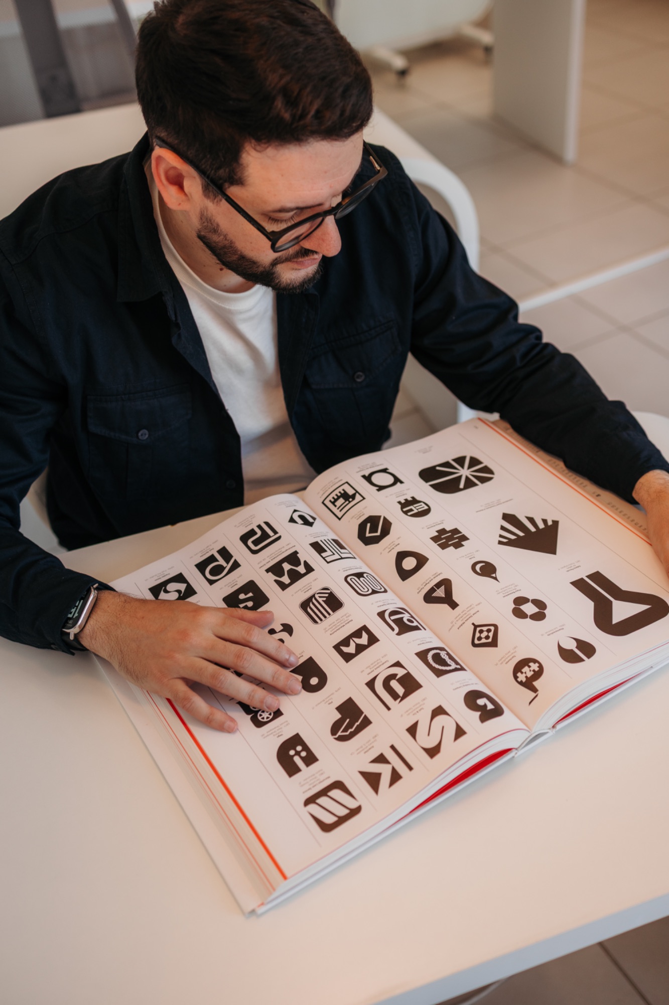 Antonio folheando um livro de marcas clássicas